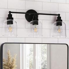 a bathroom vanity light with three clear glass globes on the top and one black metal frame