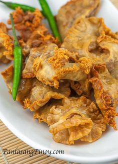 some fried food on a white plate with green beans