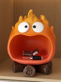 an orange object with eyes and mouth sitting on top of a shelf