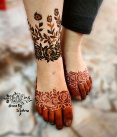 a woman's feet with henna tattoos on them and flowers in the middle