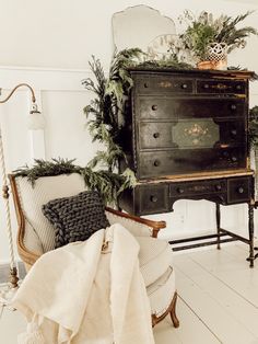 an old dresser is decorated with greenery and other holiday decorations in this white room