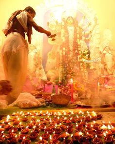 an image of a woman lighting candles in front of a wall with the words durag pujor subbedha written on it