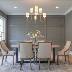 a dining room table with four chairs and a chandelier hanging from the ceiling