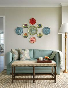 a living room with blue couches and plates on the wall above it's coffee table