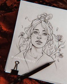 a drawing of a woman with flowers in her hair on top of a piece of paper