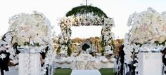 an outdoor wedding setup with white flowers and greenery at the end of the aisle