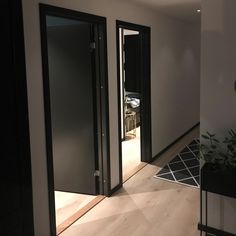 an empty room with two black doors and a plant on the floor in front of it