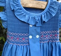 a blue dress is hanging on a wooden hanger