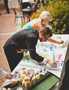 a man and woman are painting on a table