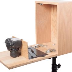 a camera is sitting in a wooden box on a tripod with the door open