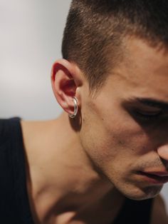 a man with ear piercings looking down at his cell phone while wearing a black tank top