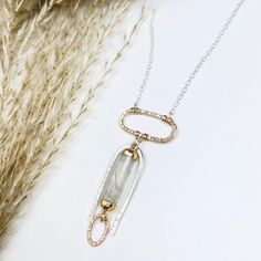 An archway of silver is textured by hand and surrounds a barrel of rutilated quartz, dropping from a gold oval pendant. Beams of gold pass through this unique gemstone accenting the tiny gold link dropping from it. •Sterling Silver and 14k Gold Filled •Rutilated Quartz •Pendant Dimensions: 1.75 x 3/4" •Length: 17" Gold Link, Jewelry Repair, Unique Gemstones, Oval Pendant, Rutilated Quartz, Quartz Pendant, Semi Precious Gemstones, Beams, Semi Precious