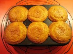 six muffins sitting on top of a wire rack next to an orange table