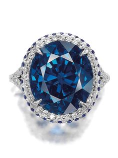 a blue and white diamond ring with diamonds around it's center, set in 18k white gold