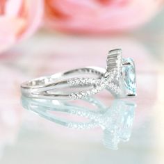 a close up view of a diamond ring with flowers in the background