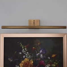 a painting hanging on the wall with flowers in it