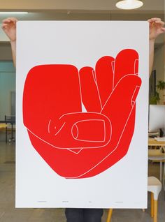 a person holding up a red and white poster