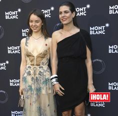 two women standing next to each other in front of a mont blanc logo sign and posing for the camera