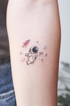 a tattoo on the arm of a person with an astronaut's space shuttle in the background