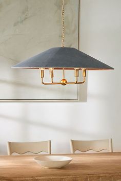 a dining room table with a bowl on it and a lamp hanging from the ceiling