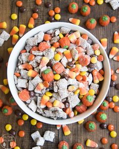 a white bowl filled with candy corn and candies on top of a wooden table