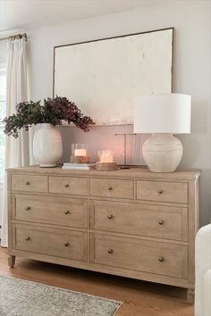 a dresser with two vases on top of it and a candle in the middle