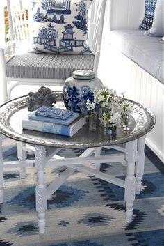 a living room with blue and white decor on the table, couches and pillows