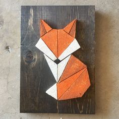 an orange and white origami fox sitting on top of a wooden board