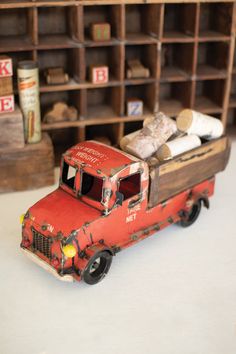 an old red truck sitting in front of a shelf filled with books and other items