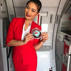 a woman in a red suit holding an award on the inside of an airplane cabin