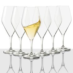 six wine glasses with white wine in them