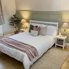 a white bed sitting in a bedroom on top of a hard wood floor next to two lamps