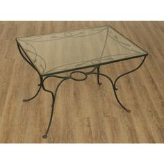 a glass table with wrought iron legs on wooden flooring and hard wood flooring