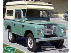 an old green land rover is parked on the street