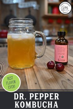 a glass mug filled with liquid sitting on top of a wooden table next to an apple