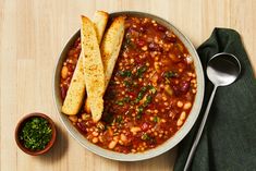 a bowl filled with beans and bread next to a spoon