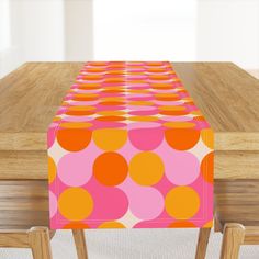 an orange and pink polka dot table runner on top of a wooden dining room table