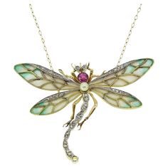 Here we have an outstanding necklace crafted during the pinnacle of the Art Nouveau movement. This rare and unique piece has been curated from a warm 18ct yellow gold into the shape of a dragonfly and displays a breathtaking use of the plique-a-jour enamelling method. The French word plique-a-jour translates to "letting in daylight”; it is a technique used dating back to 6th century AD. This method could take up to a few months to finish and is a very difficult and arduous process. During the Art Nouveau period, the French revived the plique-a-jour technique, and this dragonfly pendant is a stunning example of the fine French craftsmanship produced in that era. This one of a kind piece further showcases a rich pink sapphire, rounded natural pearl and rose cut diamoind set head, body and wi Dragonfly Art Nouveau, Art Deco Pendant Necklace, Art Nouveau Necklaces, Art Nouveau Pendant, French Word, Nouveau Jewelry, Antique Jewelry Necklace, Dragonfly Necklace, Art Deco Pendant