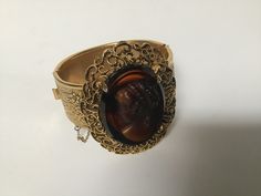 "Free shipping to the USA and Canada. A remarkable Victorian style cameo cuff bracelet.  Simply exquisite with stunning details on this beautiful bracelet.  The clasp is a hinged slide in perfect working condition and has a safety chain.  The cameo is an early celluloid and a wonderful piece of vintage jewelry. Measurements: 7\" circumference  1\" band width Cameo: 1 5/8\" 1 1/4\"" Antique Cuff Bracelet For Formal Occasions, Antique Hinged Cuff Bracelet For Formal Occasions, Vintage Cuff Bracelet With Intricate Design For Formal Events, Vintage Cuff Bracelet With Intricate Design For Formal Occasions, Antique Hinged Bracelet For Formal Occasions, Vintage Hinged Bangle For Formal Occasions, Antique Hinged Bracelets For Formal Occasions, Vintage Carved Jewelry For Formal Occasions, Antique Oval Bangle For Formal Occasions