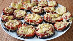 a white plate topped with stuffed tomatoes and other toppings on top of a wooden table