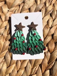 the earrings are made out of green and brown paper with red berries on them,