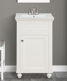 a white bathroom vanity with two faucets and a mirror on the wall above it