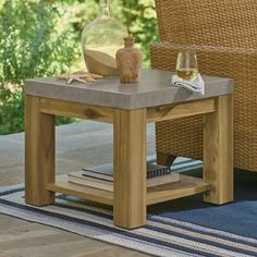 a wooden table with a vase and books on it next to a wicker chair