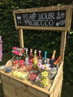 an outdoor bar with various drinks and snacks on the table, including lemons, raspberries, watermelon, and more