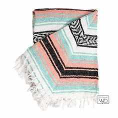 a pink, blue and green blanket with fringes on the ends is laying next to each other