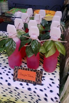 there are some pink vases with green leaves on the table and an orange tag that says jungle house