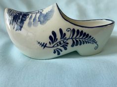 a blue and white ceramic shoe shaped object on a light blue clothed surface,