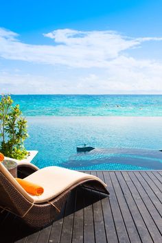 an empty lounge chair sitting on top of a wooden deck