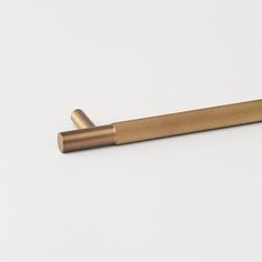 a metal object on a white surface with a wooden stick sticking out of it's side