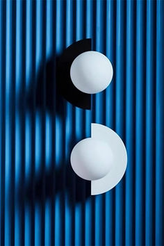 two black and white lights are hanging on a blue metal wall with vertical lines in the background